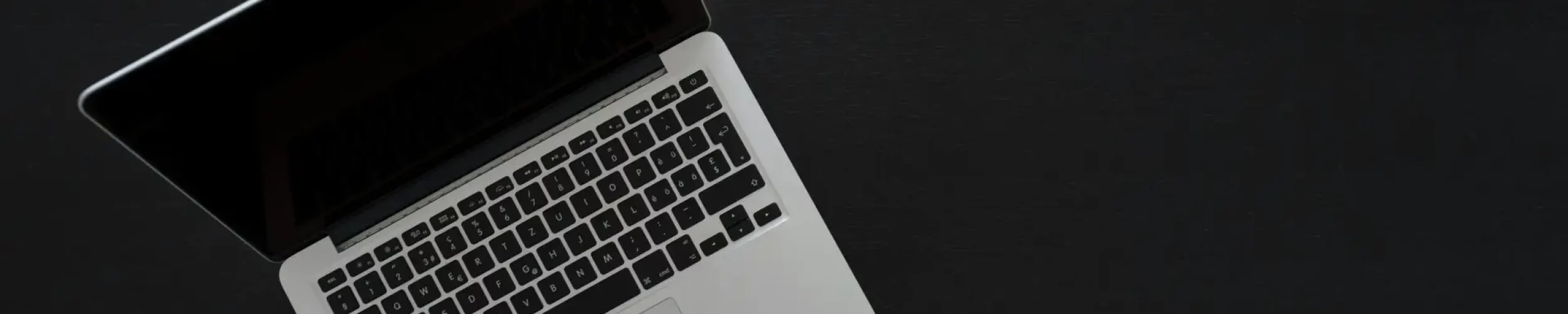 Overhead view of a MacBook laptop on a dark desk, showcasing modern technology and minimalism.